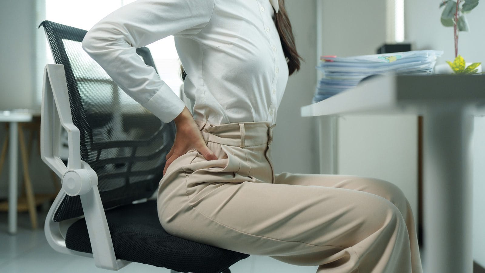 A woman suffers lower back pain because of an uncomfortable office chair.