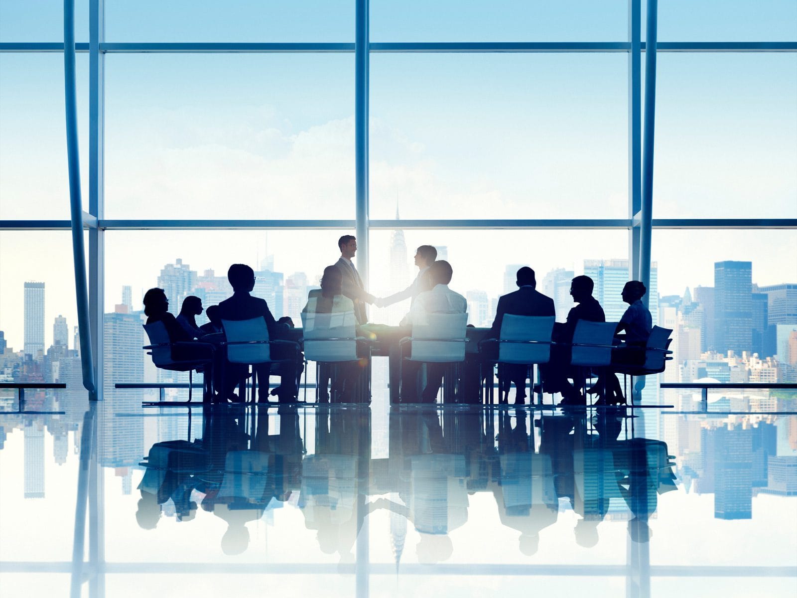 A silhouette of 10 people at a conference table in a corporate high-rise office.