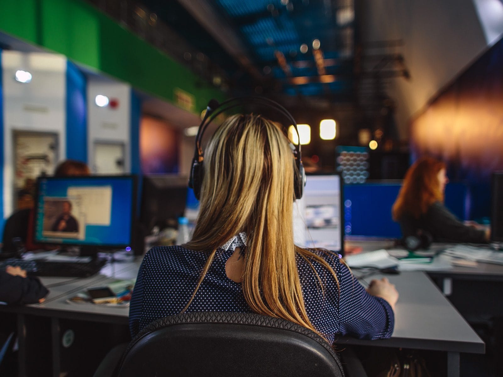 A view from behind an editor inside of a busy newsroom.
