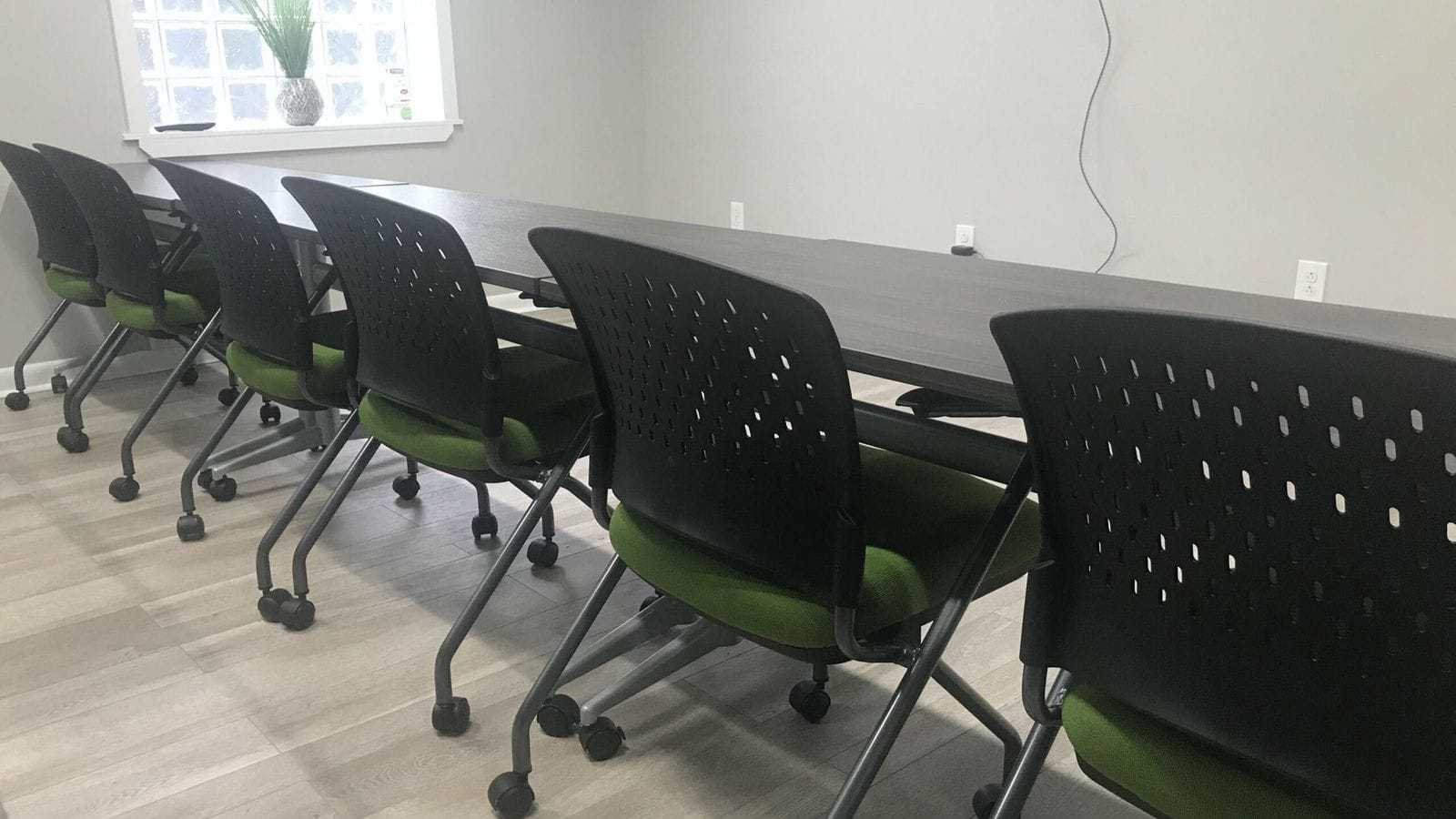 Gently used gray conference table with green nesting chairs ready for donation