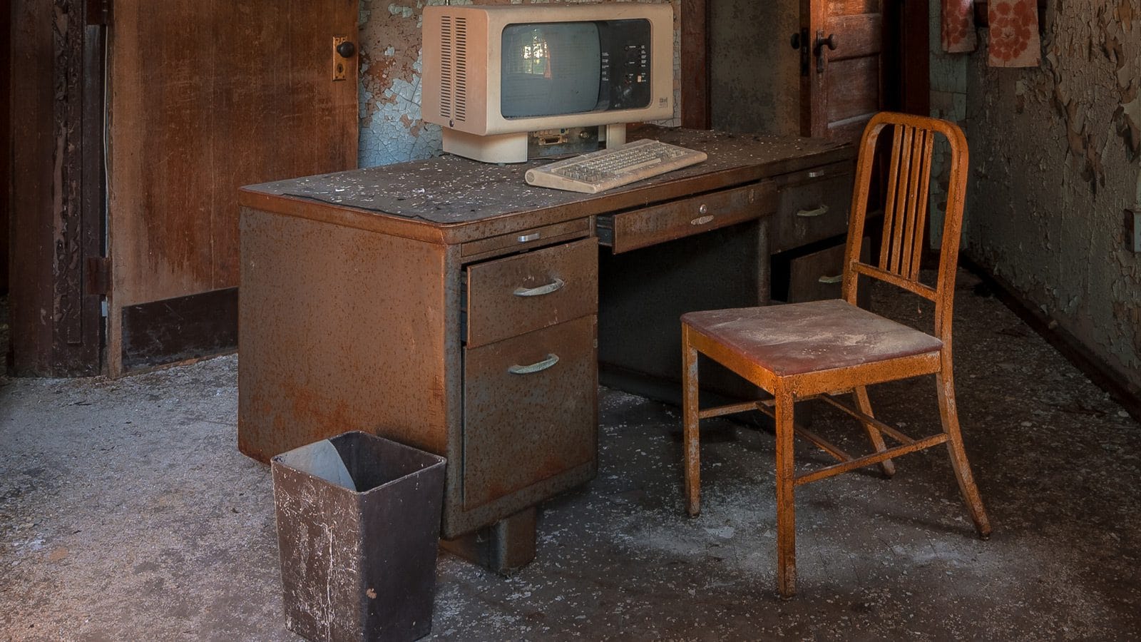 An old office desk, chair, and an ancient computer.