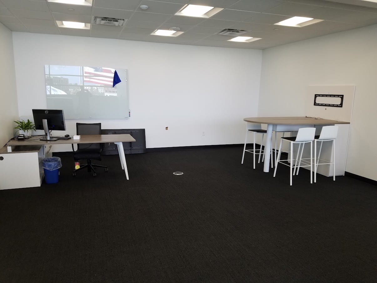 Private office with a height-adjustable desk and a high-top meeting table at United Grinding North America